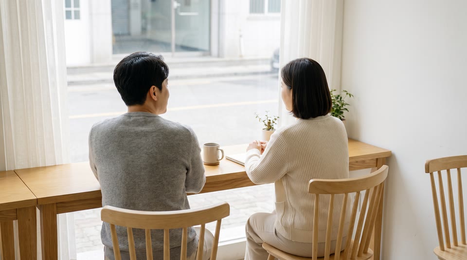 카페 창가에 마주 앉아 대화하는 두 사람의 뒷모습