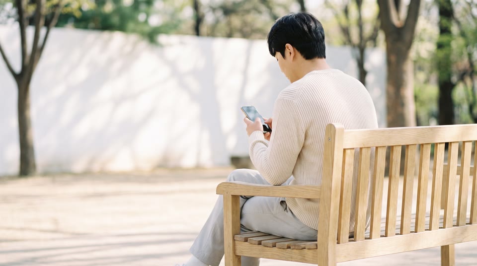 핸드폰을 보며 고민에 빠진 사람의 뒷모습